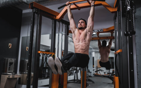 Man doing pull-ups in a gym.
