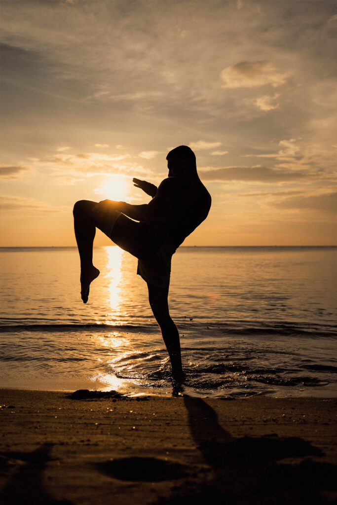 A person is kicking on the beach at sunset.