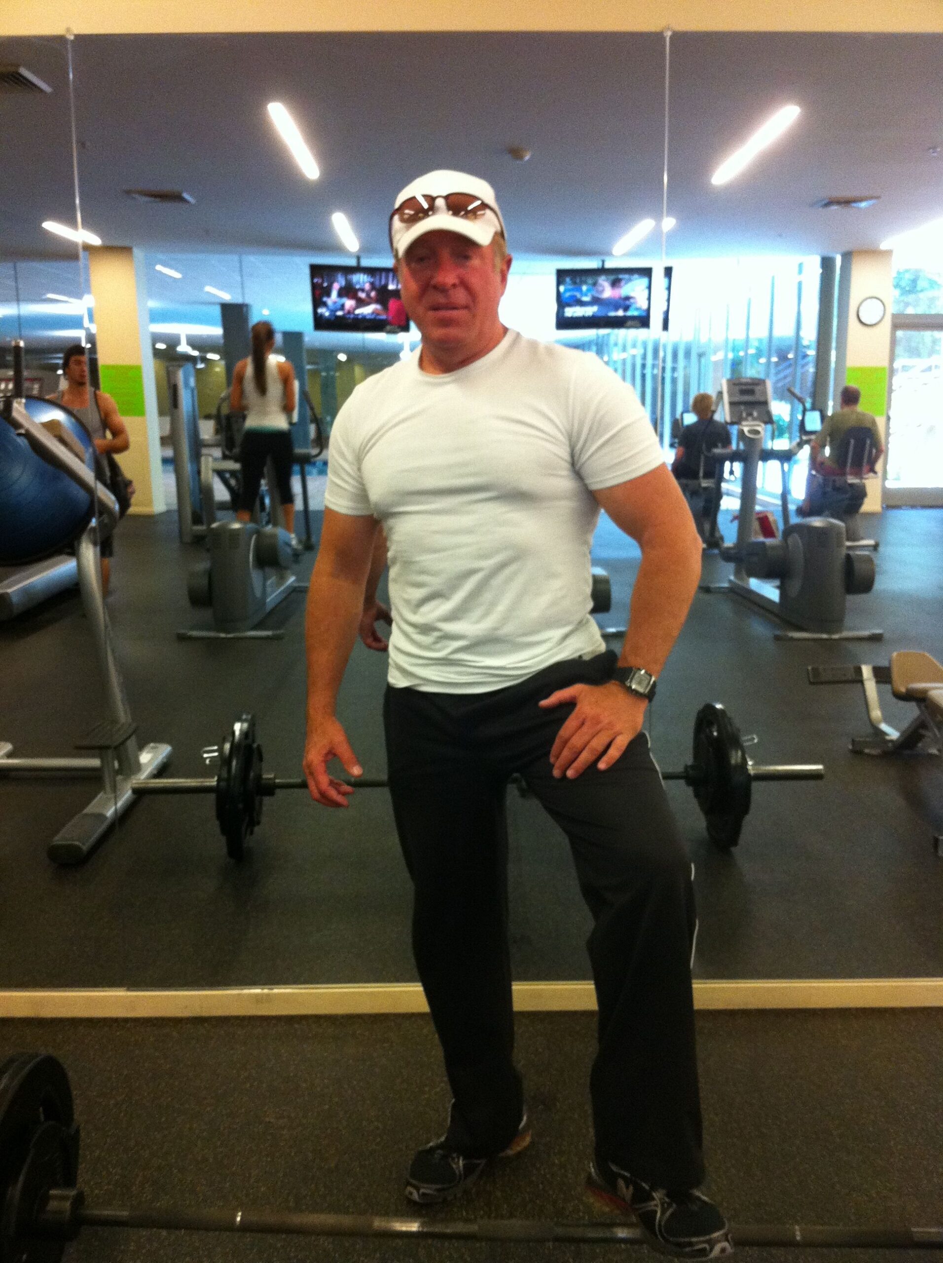 A man in white shirt holding a barbell.